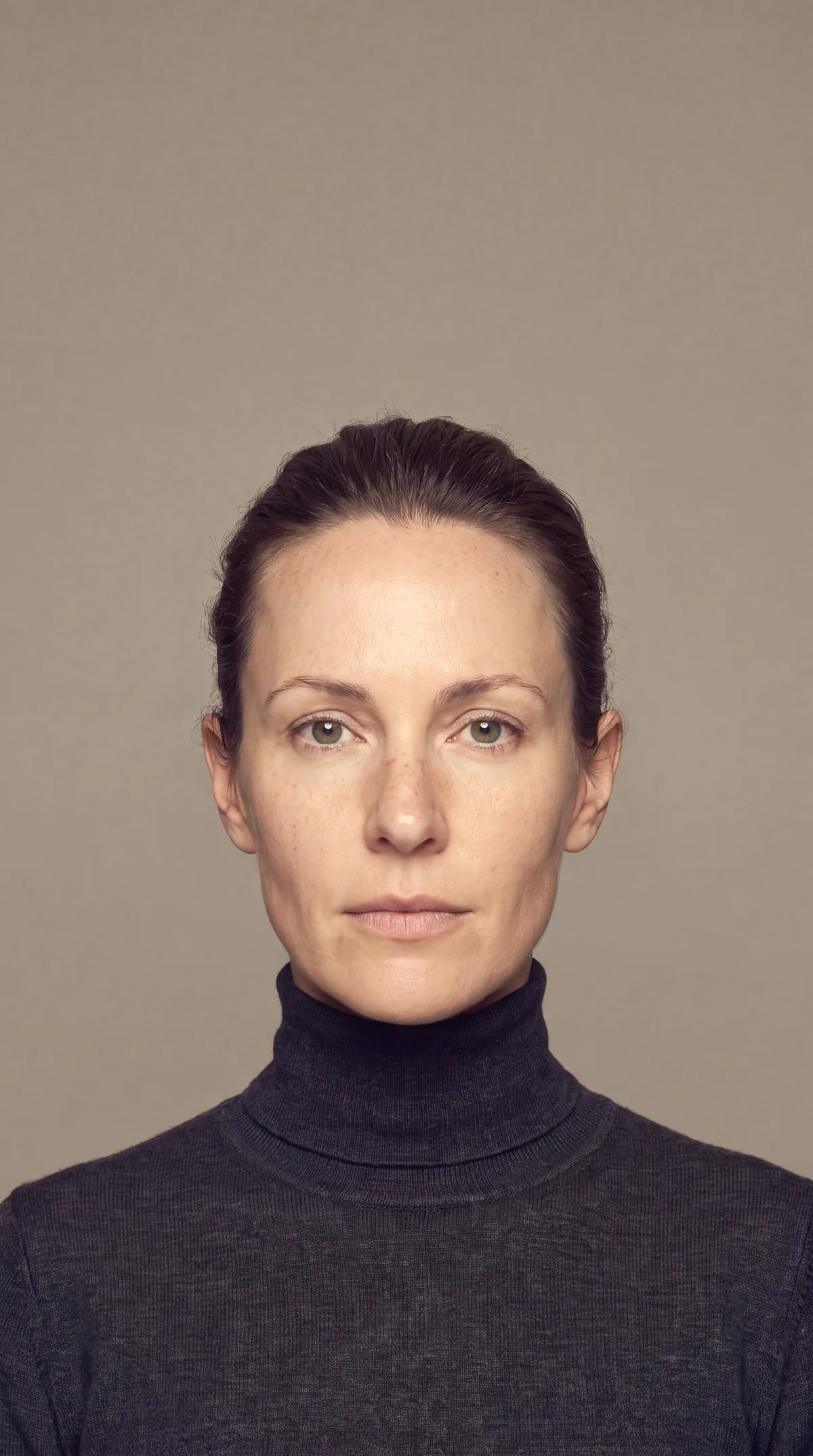 Frau im dunklen Rollkragenpullover vor warmgrauem Grund, frontal, illustratives Motiv